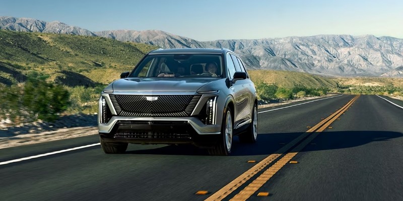2026 Cadillac SUV driving on a scenic mountain road.