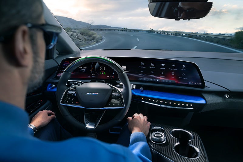 Front View of the 2026 OPTIQ-V Driving Through the Dusk Utilizing its Headlights | Val Ward Cadillac in Fort Myers FL