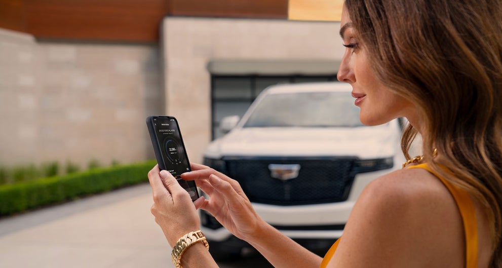 lady checking her mobile with a Cadillac vehicle background | Val Ward Cadillac in Fort Myers FL